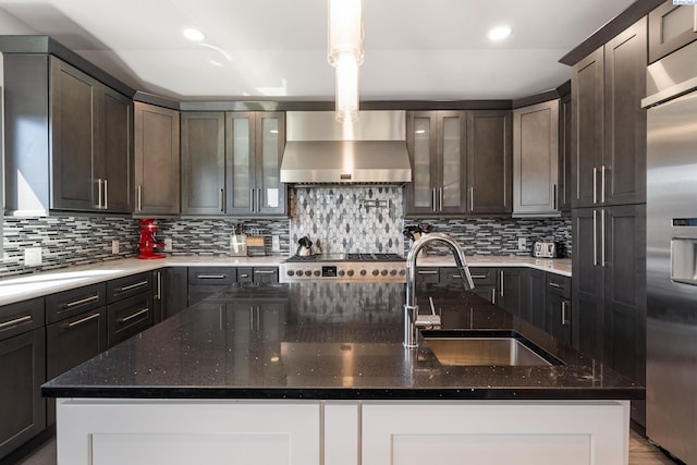 9115 W Maple Dr, Pasco, WA 99301 - kitchen featuring wall chimney range hood, high end fridge, dark stone counters, recessed lighting, and a kitchen island with sink