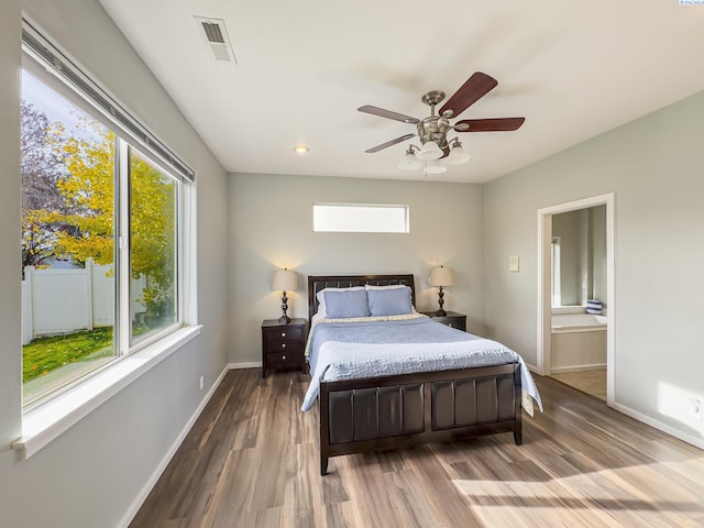 bedroom featuring visible vents, baseboards, ceiling fan, wood finished floors, and ensuite bathroom