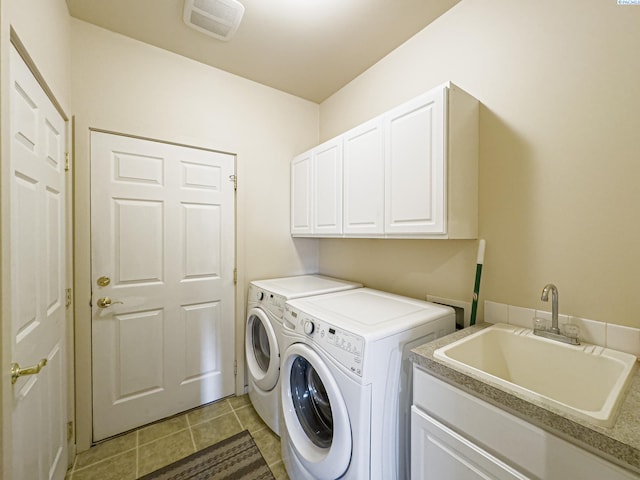 laundry area with cabinet space, light tile patterned floors, visible vents, washing machine and dryer, and a sink