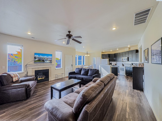 living area with dark wood-style floors, a tile fireplace, visible vents, and recessed lighting