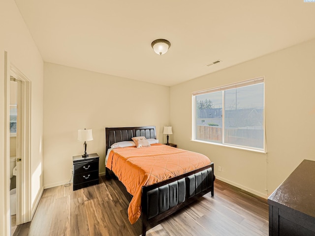 bedroom featuring baseboards, visible vents, and wood finished floors