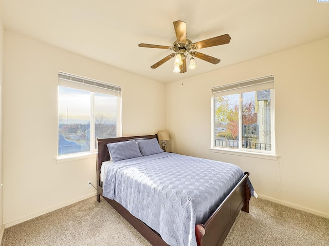 carpeted bedroom with ceiling fan and baseboards