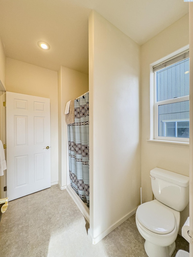 bathroom featuring a shower with shower curtain, baseboards, toilet, and tile patterned floors