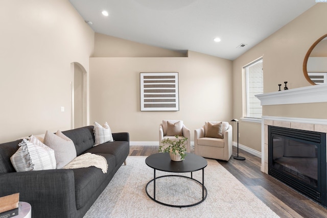 living room featuring a tile fireplace, lofted ceiling, and hardwood / wood-style floors