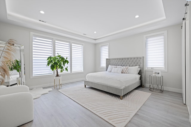 bedroom featuring light wood-type flooring and a tray ceiling