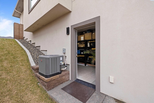 entrance to property with cooling unit and a lawn