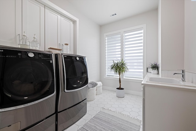 laundry room featuring sink, light tile patterned floors, cabinets, and independent washer and dryer