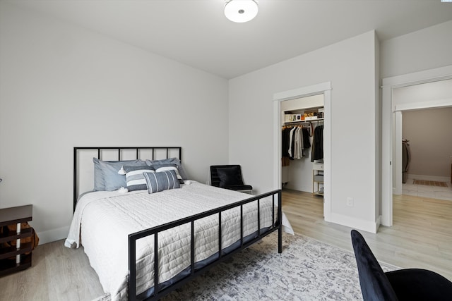 bedroom featuring a walk in closet, light hardwood / wood-style floors, and a closet