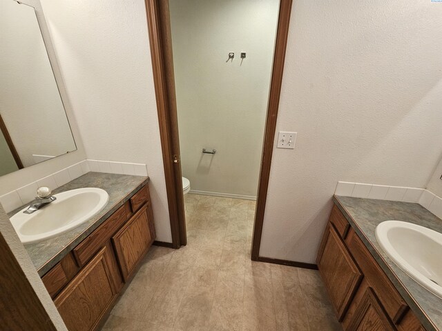 1135-1137 NE Indiana St, Pullman, WA 99163 - bathroom featuring a sink, baseboards, toilet, and two vanities