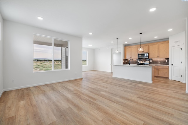 kitchen with pendant lighting, sink, appliances with stainless steel finishes, an island with sink, and decorative backsplash