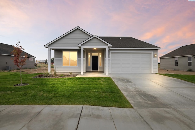 view of front of house with a garage, central air condition unit, and a lawn