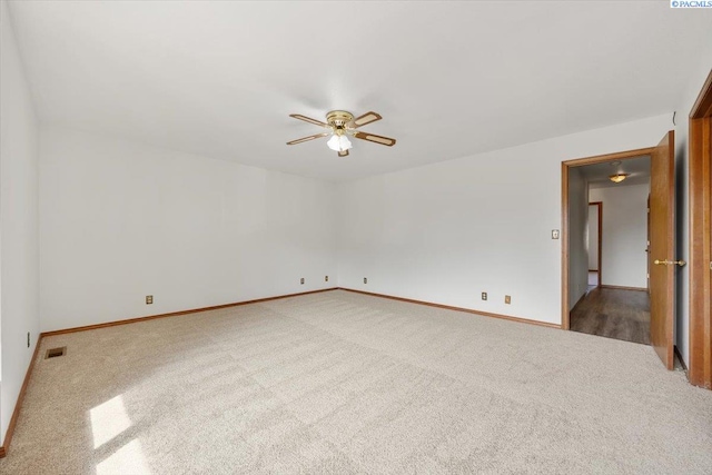 unfurnished room with a ceiling fan, visible vents, carpet, and baseboards