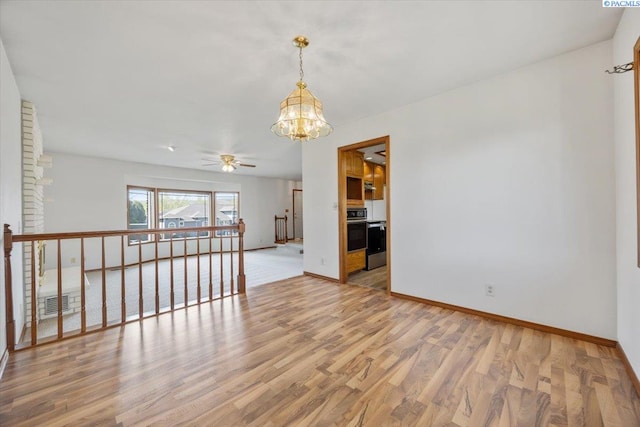 unfurnished room featuring baseboards, visible vents, wood finished floors, and ceiling fan with notable chandelier
