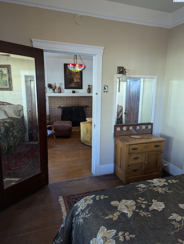 bedroom featuring ornamental molding, a brick fireplace, and dark wood-type flooring