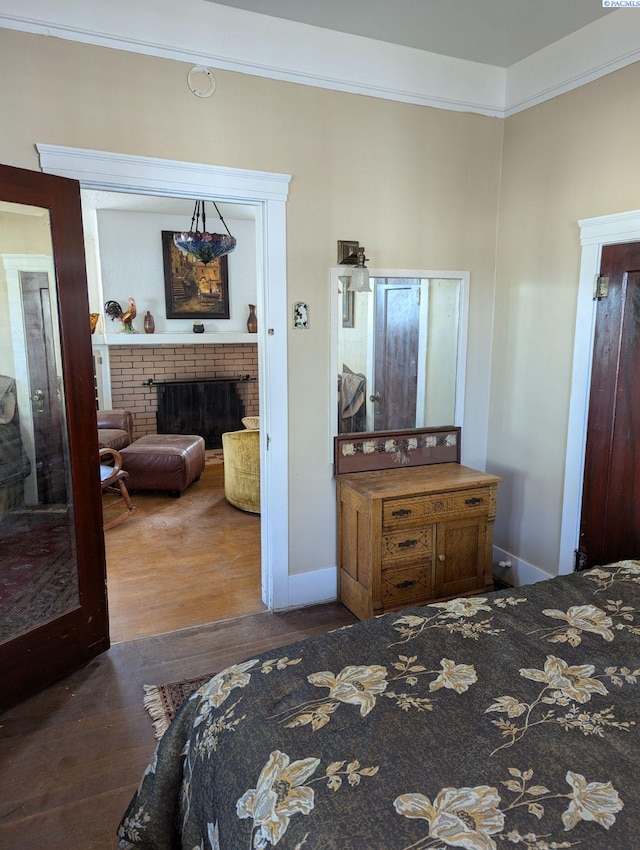 bedroom featuring dark hardwood / wood-style flooring, a brick fireplace, and crown molding