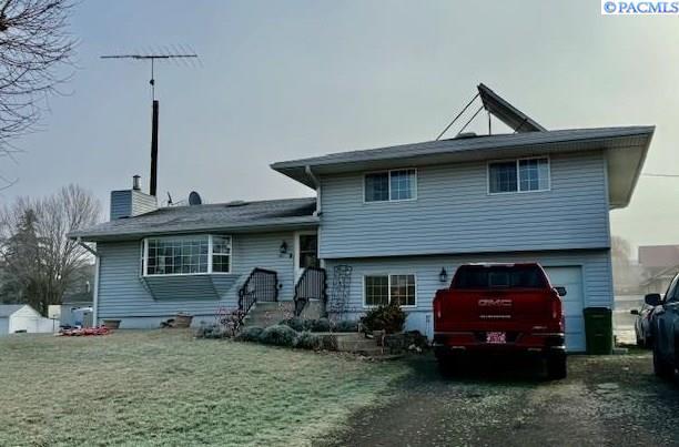 rear view of property featuring a yard and a garage