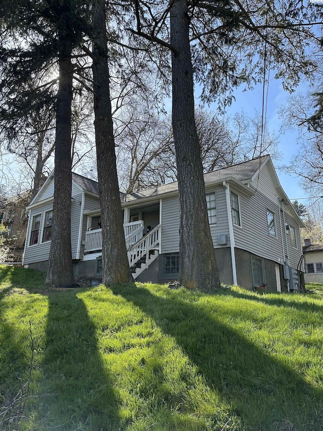 view of side of property with a lawn and covered porch