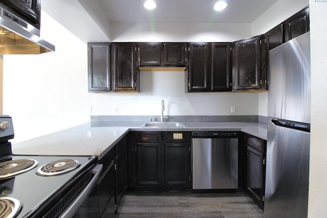 kitchen featuring exhaust hood, dark wood-style flooring, stainless steel appliances, a sink, and recessed lighting