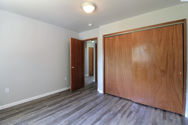 unfurnished bedroom featuring a closet, baseboards, and wood finished floors