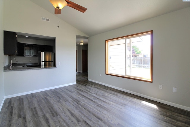 unfurnished living room with vaulted ceiling, a sink, visible vents, and baseboards