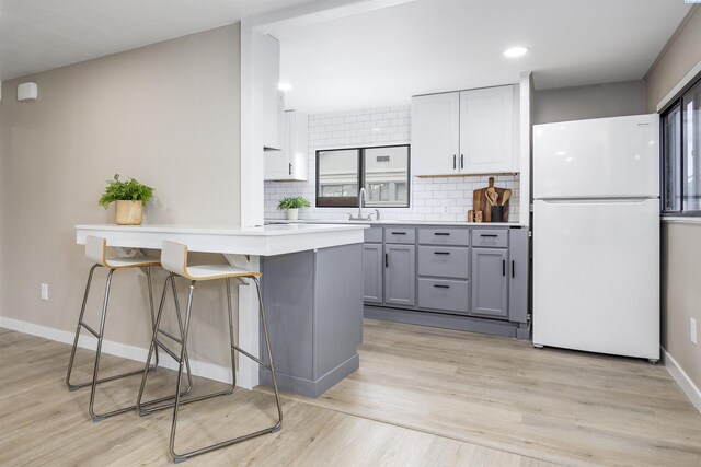 1517 Perkins Ave, Richland, WA 99354 - kitchen featuring freestanding refrigerator, gray cabinets, a kitchen bar, tasteful backsplash, and a peninsula