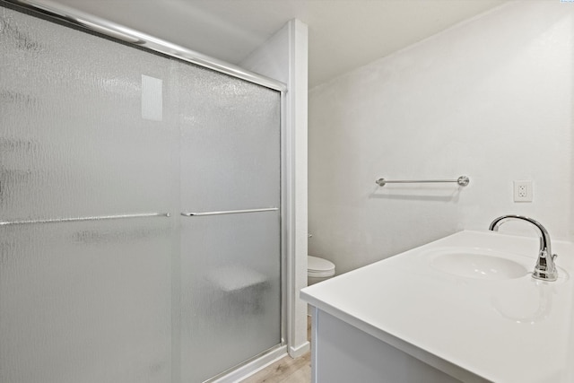 full bathroom with wood finished floors, a stall shower, vanity, and toilet