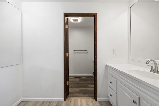 bathroom featuring baseboards, wood finished floors, and vanity