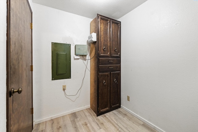 interior space with baseboards, electric panel, and light wood-style floors