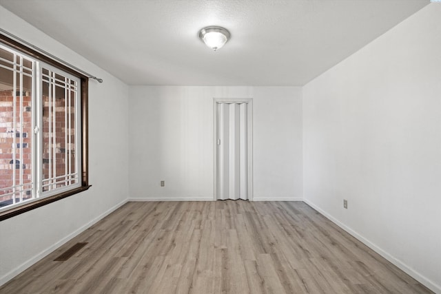 spare room featuring visible vents, baseboards, and wood finished floors