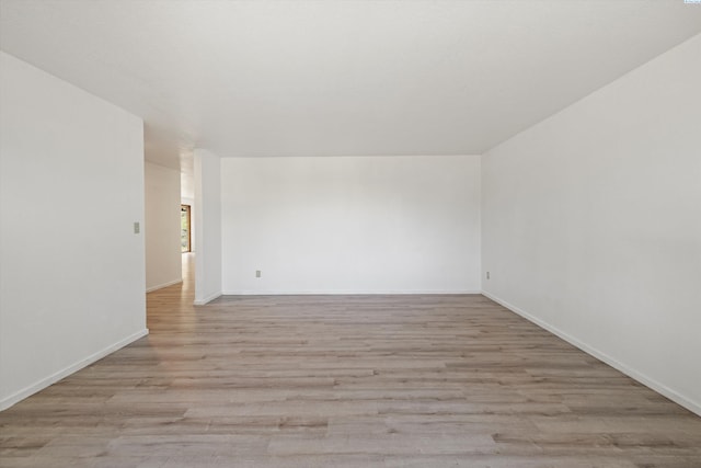 spare room featuring light wood-type flooring and baseboards