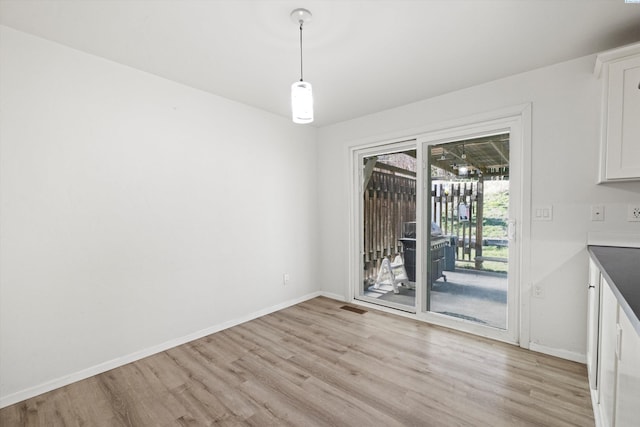 unfurnished dining area with light wood-style flooring and baseboards