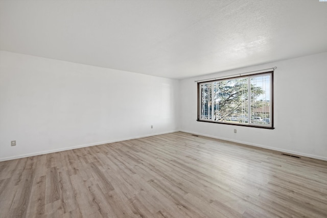 unfurnished room featuring visible vents, baseboards, and wood finished floors