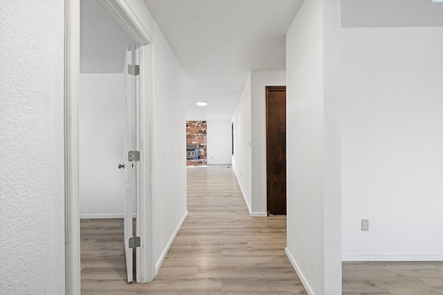 corridor featuring baseboards and light wood-style floors