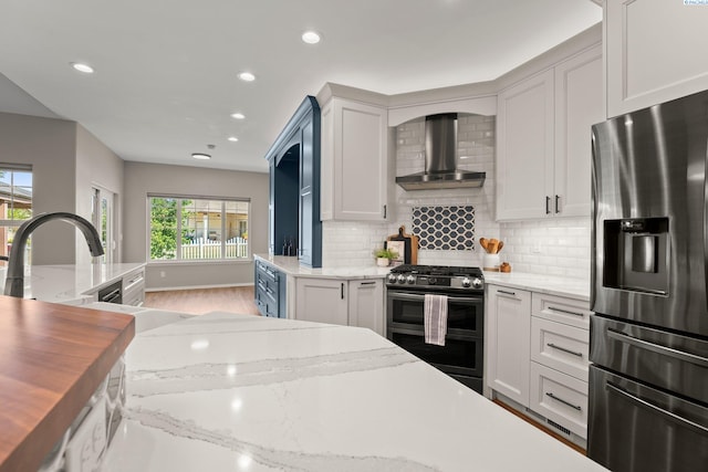 19 Ivy Ln, Pasco, WA 99301 - kitchen with stainless steel appliances, wall chimney exhaust hood, decorative backsplash, recessed lighting, and white cabinetry