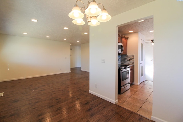 kitchen featuring decorative light fixtures, a textured ceiling, appliances with stainless steel finishes, dark hardwood / wood-style floors, and backsplash