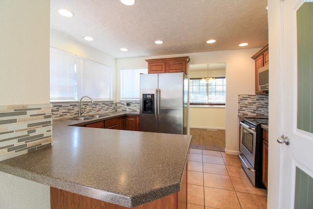 kitchen with light tile patterned flooring, appliances with stainless steel finishes, sink, decorative backsplash, and kitchen peninsula