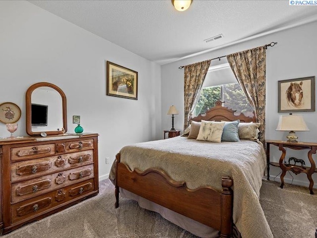 carpeted bedroom with baseboards, a textured ceiling, and visible vents
