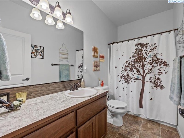 bathroom with vanity, stone finish floor, toilet, and curtained shower
