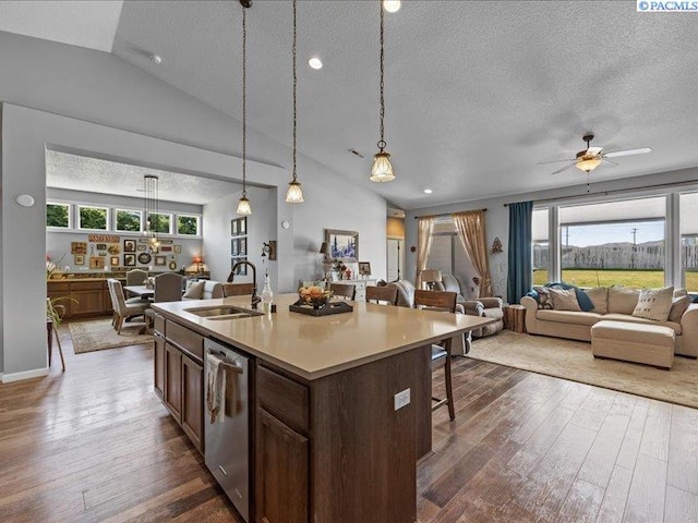 kitchen featuring a breakfast bar area, a textured ceiling, dark wood finished floors, a sink, and open floor plan