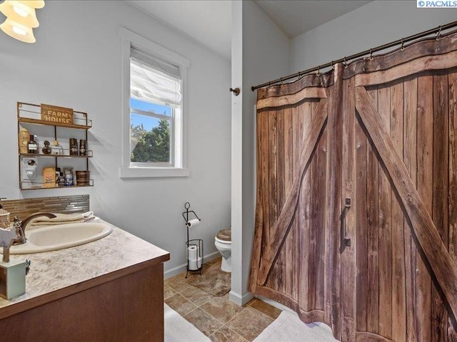 bathroom featuring toilet, baseboards, and vanity