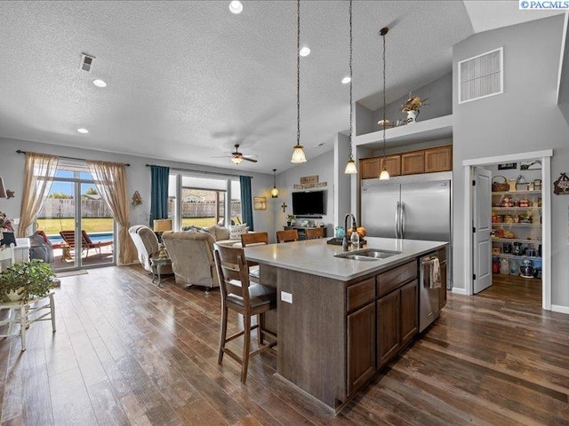 kitchen with a textured ceiling, open floor plan, appliances with stainless steel finishes, and a sink