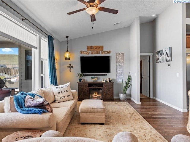 living area featuring ceiling fan, visible vents, wood finished floors, baseboards, and lofted ceiling