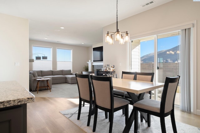 dining room featuring a chandelier, light wood-type flooring, a fireplace, visible vents, and recessed lighting