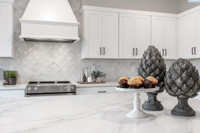 kitchen featuring stainless steel range with electric stovetop, light stone counters, white cabinetry, and custom exhaust hood