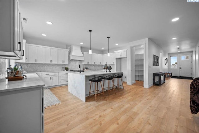 kitchen with light hardwood / wood-style flooring, a center island, white cabinets, and premium range hood