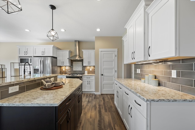 1120 S Kansas Pl, Kennewick, WA 99338 - kitchen with wall chimney range hood, decorative backsplash, dark wood-style flooring, appliances with stainless steel finishes, and white cabinetry