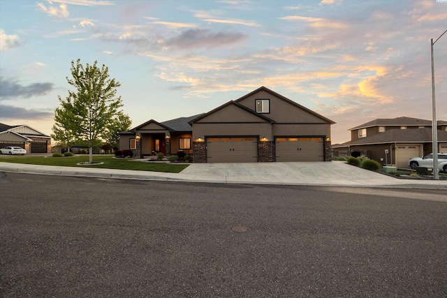 1120 S Kansas Pl, Kennewick, WA 99338 - view of front of home featuring an attached garage, driveway, stone siding, and stucco siding