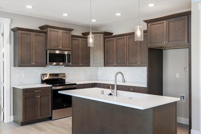 kitchen featuring sink, hanging light fixtures, light wood-type flooring, appliances with stainless steel finishes, and backsplash