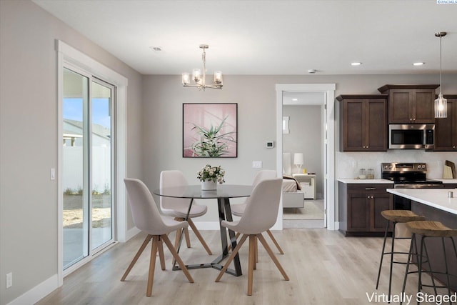 dining area with a notable chandelier and light hardwood / wood-style floors