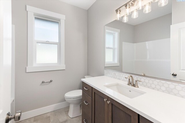 bathroom featuring decorative backsplash, vanity, walk in shower, and toilet